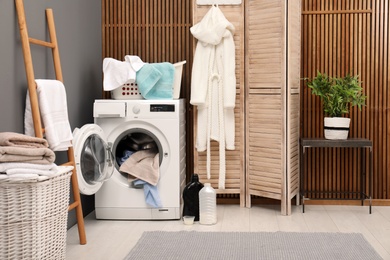 Basket with dirty towels on washing machine in modern laundry room