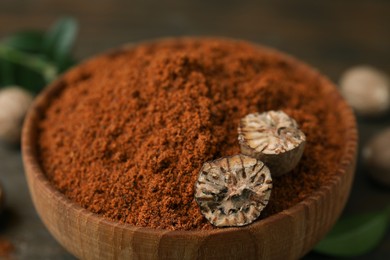 Photo of Nutmeg powder and halves of seed in bowl on table, closeup