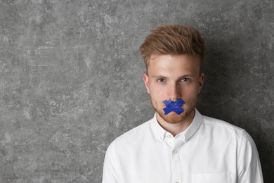 Man with taped mouth on grey background, space for text. Speech censorship
