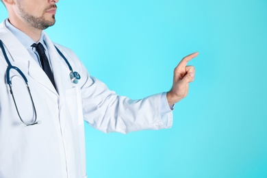 Photo of Male doctor pointing on color background, closeup