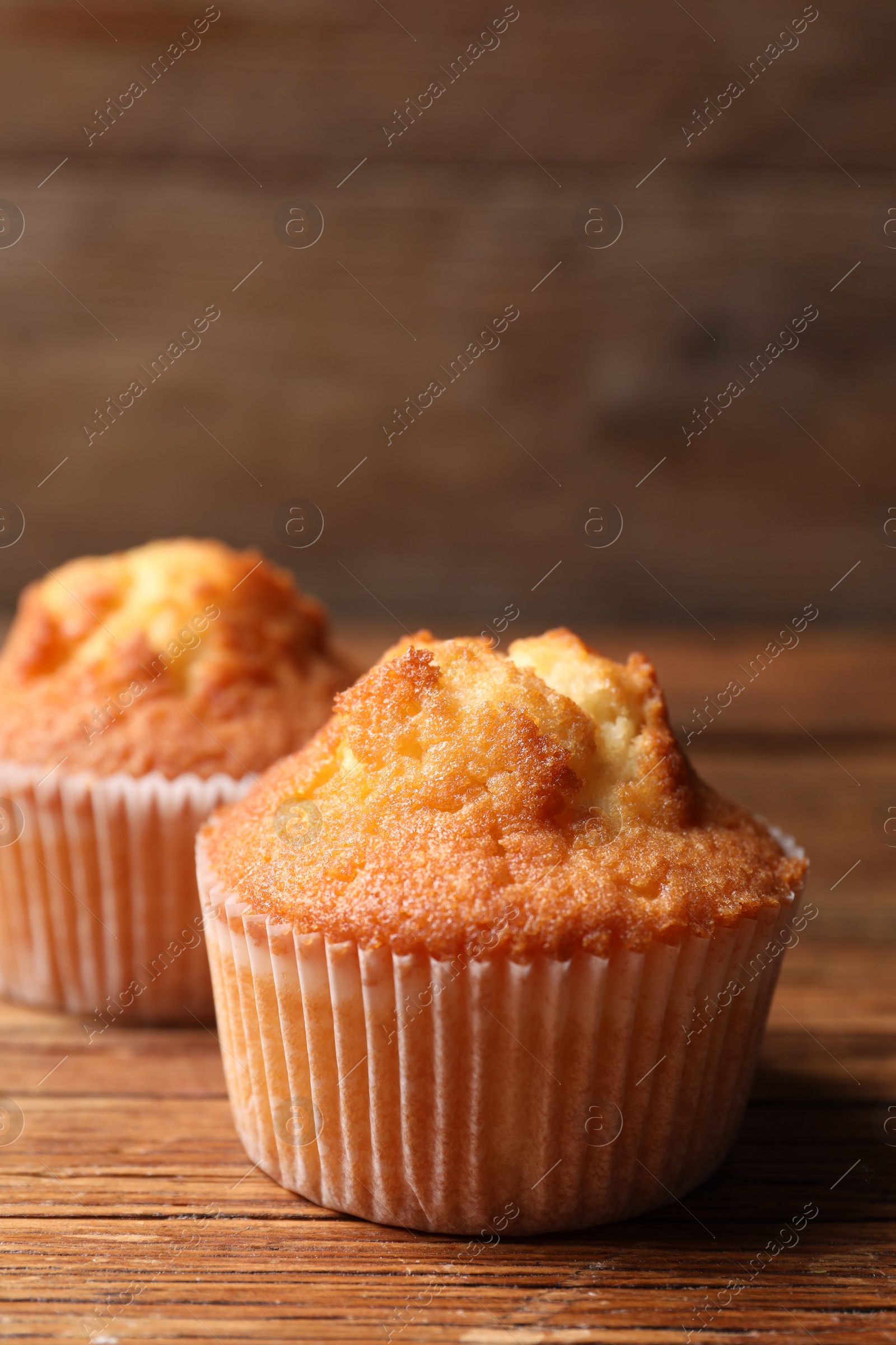 Photo of Delicious sweet muffins on wooden table, closeup. Space for text