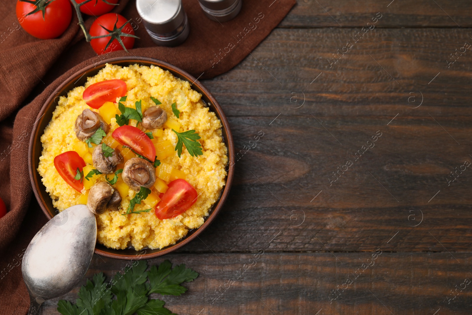 Photo of Tasty cornmeal with tomatoes, pepper and mushrooms in bowl served on wooden table, top view. Space for text