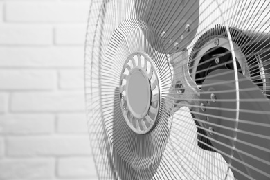 Photo of Electric fan near white brick wall, closeup. Summer heat