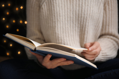 Young woman reading book at home, closeup