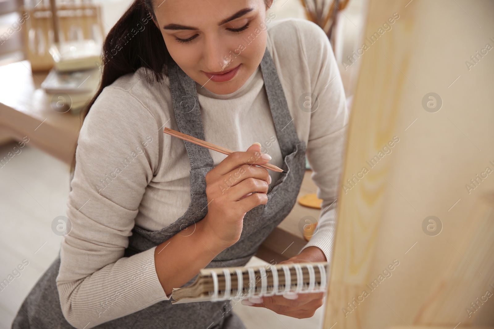 Photo of Young woman drawing in notebook at home, closeup