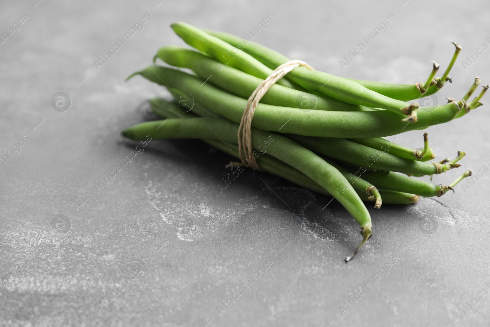 Photo of Fresh green beans on grey table, closeup