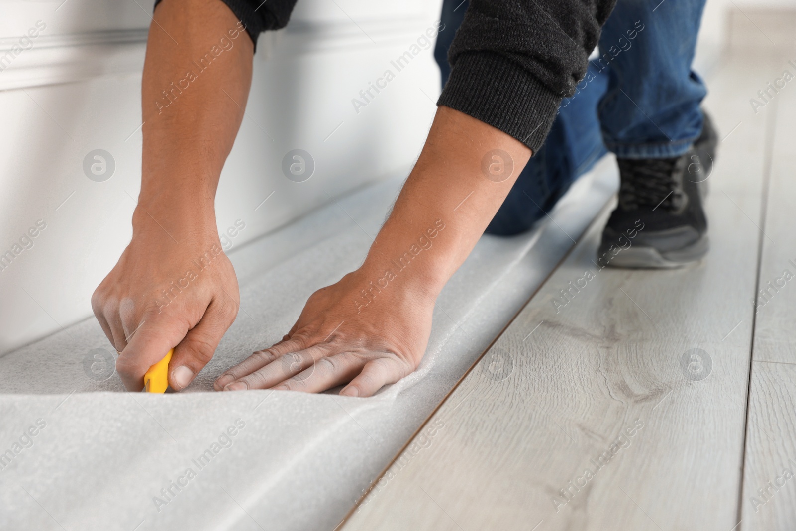 Photo of Worker installing new laminate flooring in room, closeup