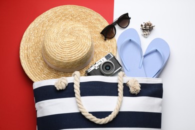 Stylish bag with beach accessories on color background, flat lay