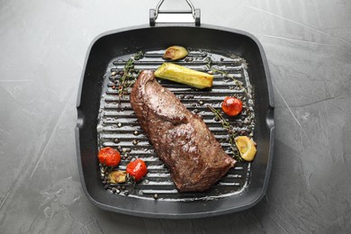 Photo of Delicious grilled beef meat and vegetables in pan on grey table, top view