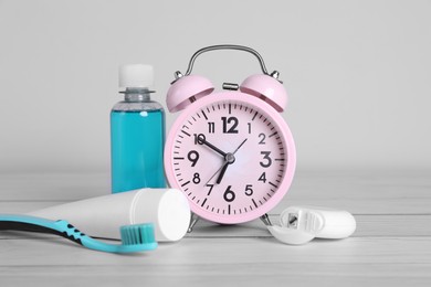 Photo of Composition with dental floss, alarm clock and different teeth care products on white wooden table
