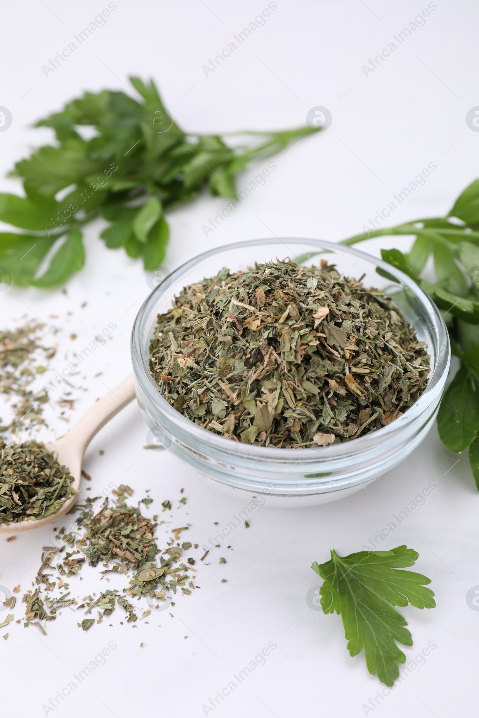 Photo of Dried aromatic parsley and fresh leaves on white table