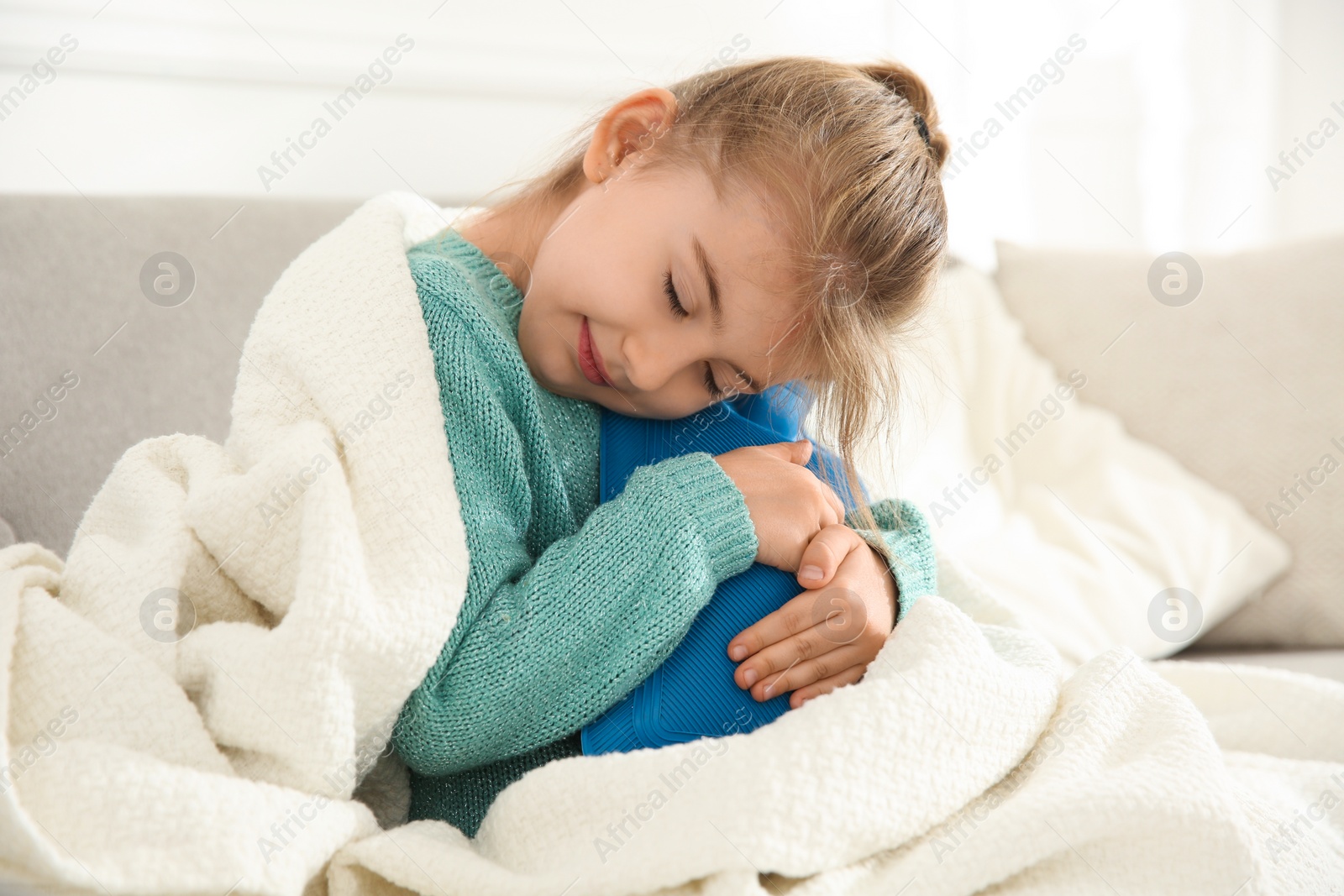 Photo of Ill girl with hot water bottle suffering from cold at home