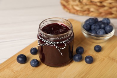 Photo of Jar of delicious blueberry jam and fresh berries on wooden table, closeup