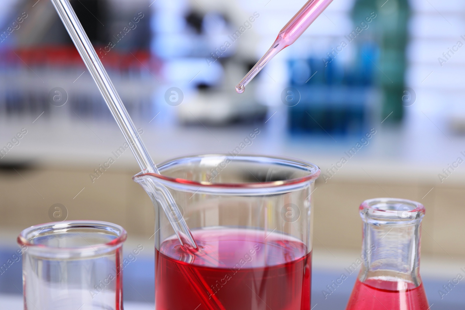 Photo of Laboratory analysis. Dripping red liquid into beaker on table, closeup