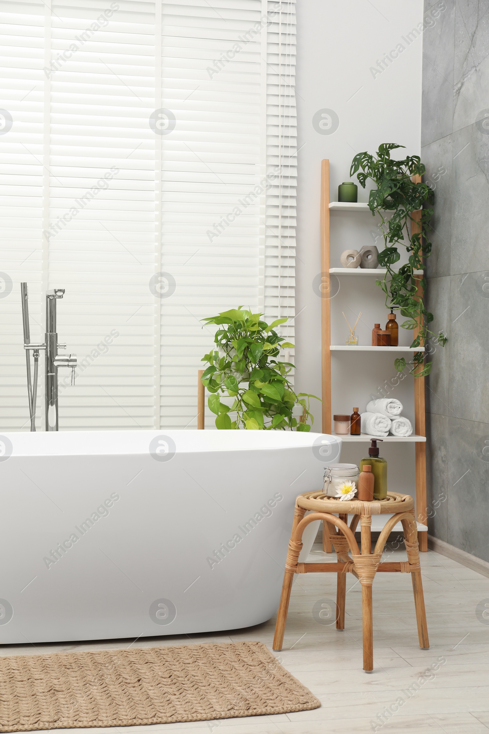 Photo of Spa day. Stylish bathroom interior with ceramic tub and green houseplants