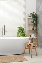 Photo of Spa day. Stylish bathroom interior with ceramic tub and green houseplants