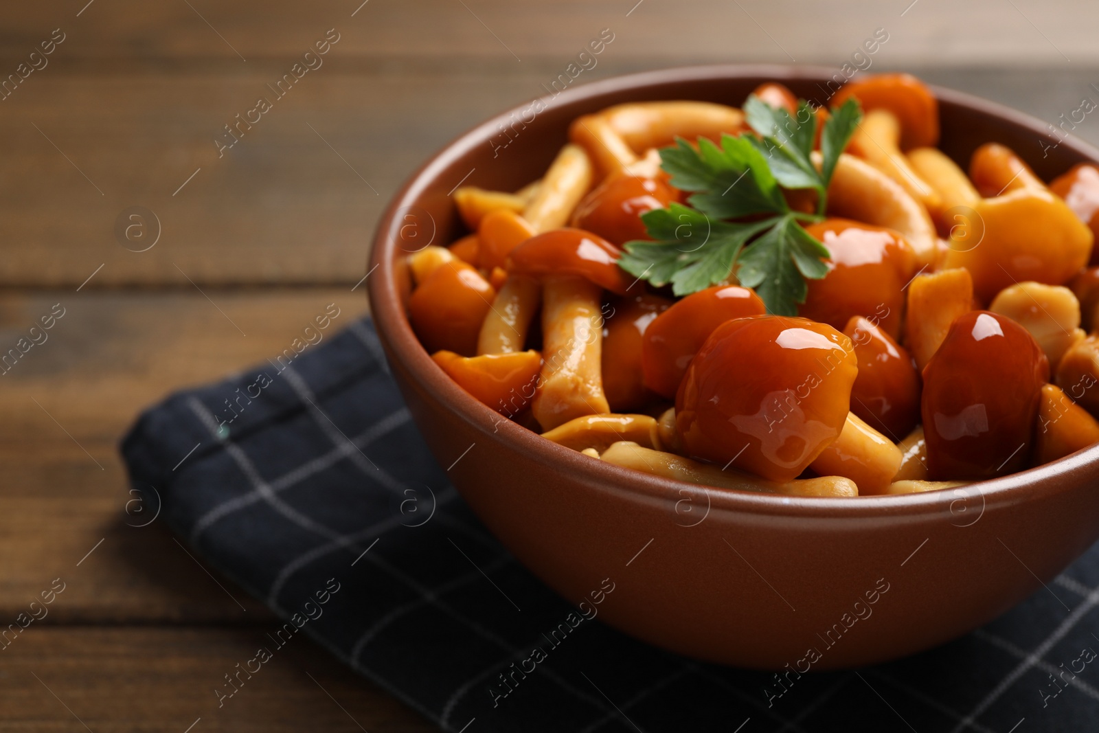 Photo of Tasty marinated mushrooms in bowl on wooden table, closeup. Space for text