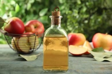 Natural apple vinegar and fresh fruits on blue wooden table