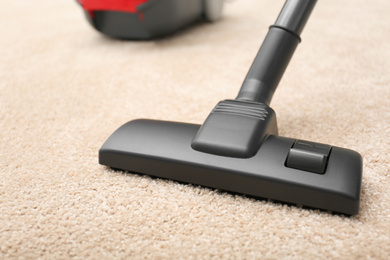 Removing dirt from carpet with vacuum cleaner indoors, closeup