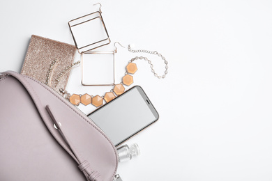 Photo of Stylish woman's bag with smartphone and accessories on white background, flat lay. Space for text