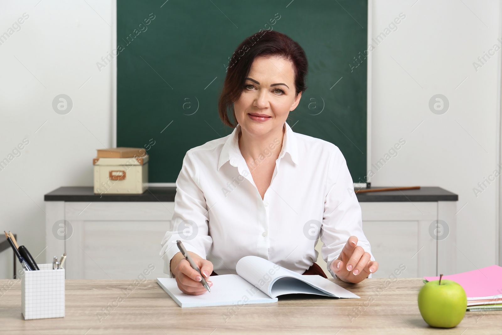 Photo of Portrait of female teacher sitting at table in classroom
