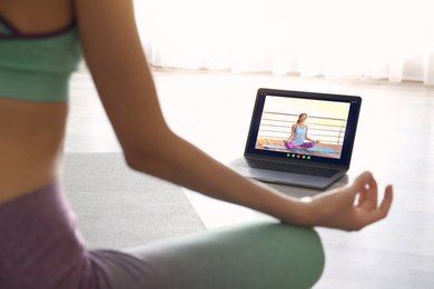 Image of Distance yoga course during coronavirus pandemic. Woman having online practice with instructor via laptop at home, closeup