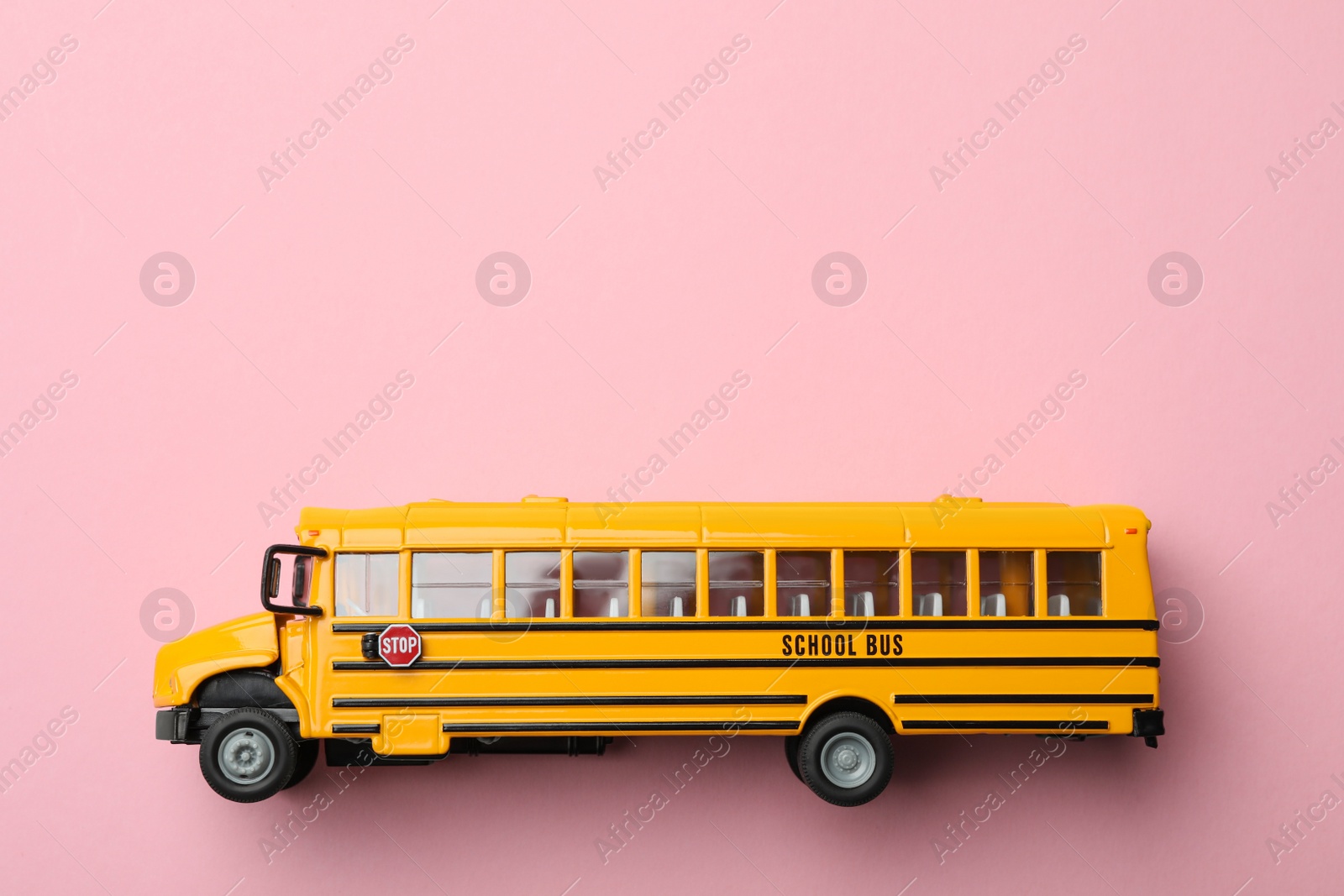 Photo of Yellow school bus on pink background, top view with space for text. Transport service