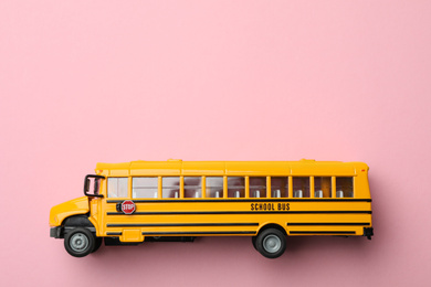 Photo of Yellow school bus on pink background, top view with space for text. Transport service