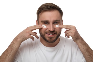 Photo of Happy young man applying facial cream on white background