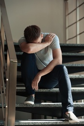 Depressed young man sitting on stairs