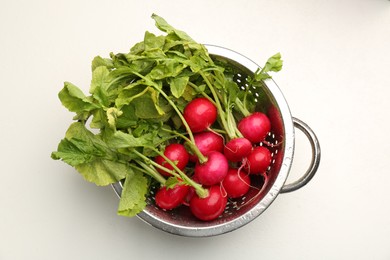 Photo of Wet radish in colander on white table, top view