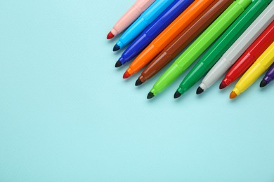 Photo of Different colorful markers on light blue background, flat lay. Space for text