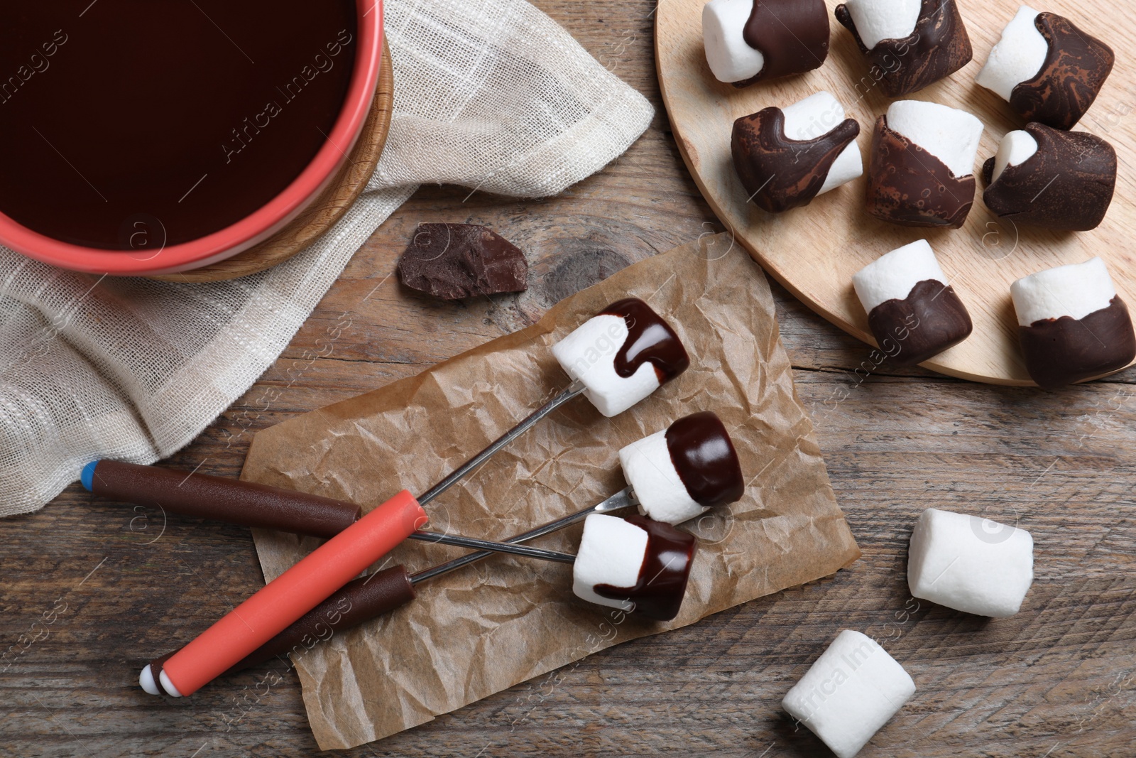 Photo of Delicious marshmallows covered with chocolate on wooden table, flat lay