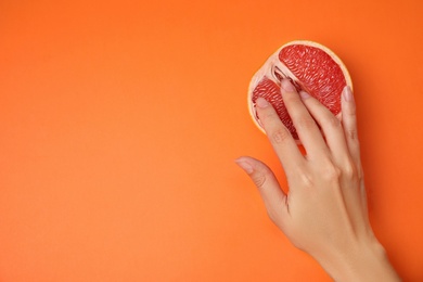 Photo of Young woman touching half of grapefruit on orange background, top view with space for text. Sex concept