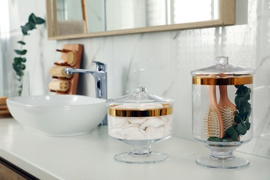 Jars with cotton pads and hairbrushes on bathroom countertop