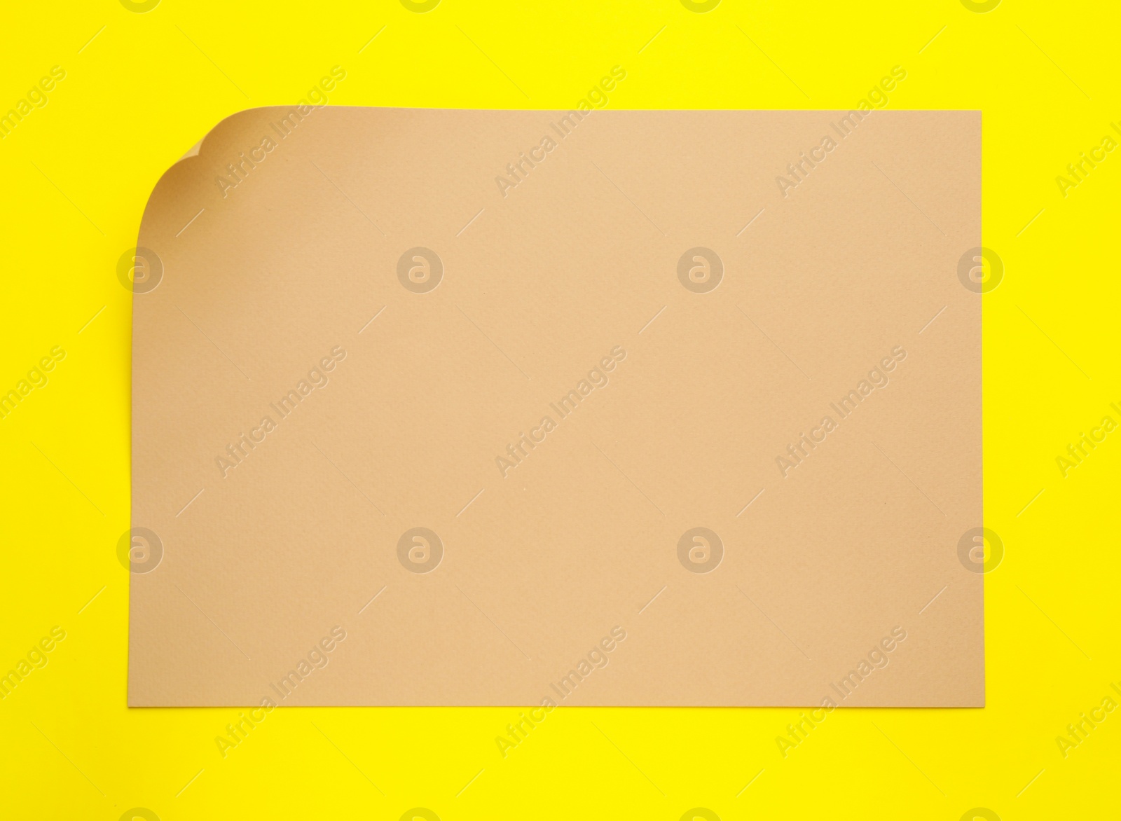 Photo of Sheet of brown paper on yellow background, top view