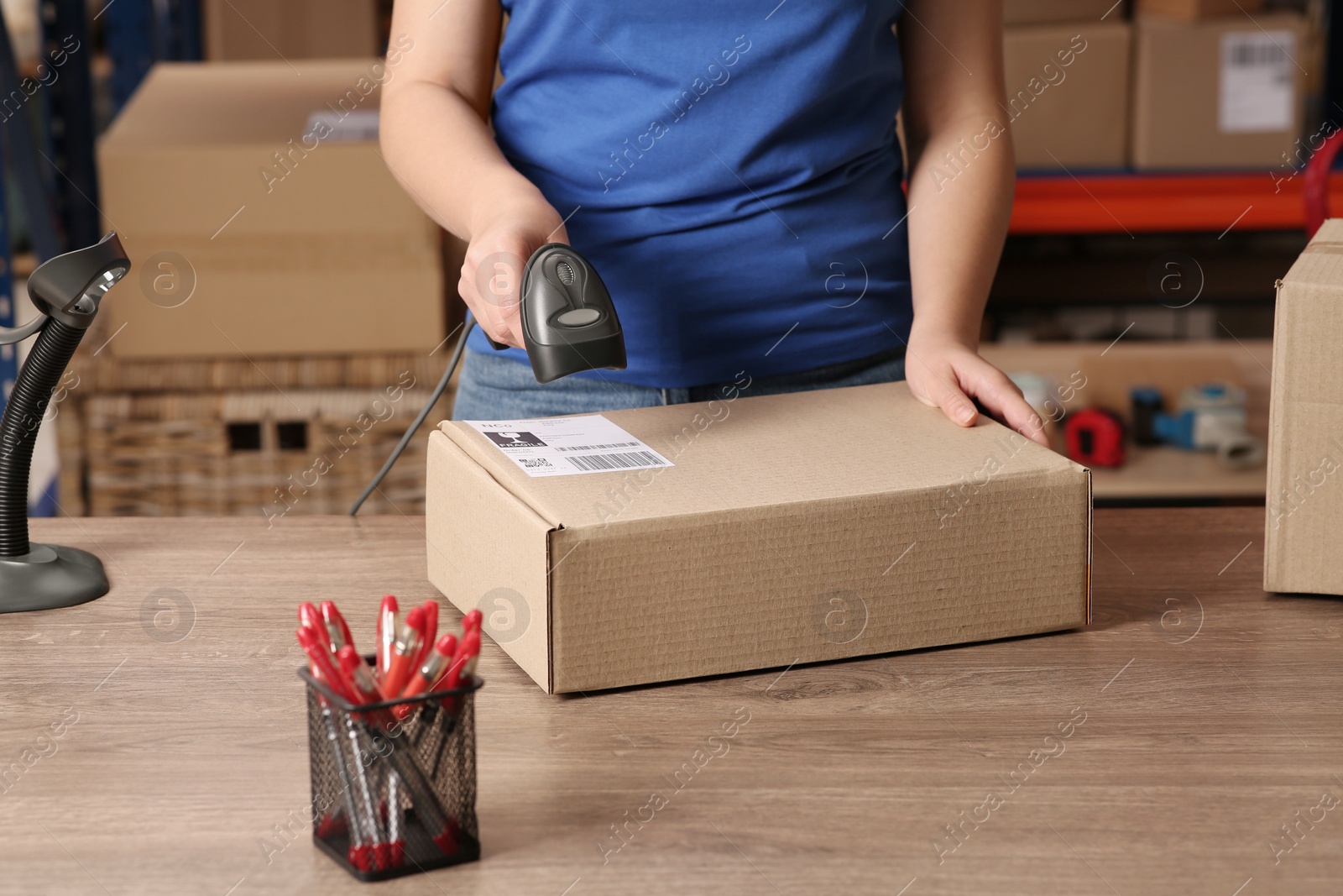 Photo of Post office worker with scanner reading parcel barcode at counter, closeup