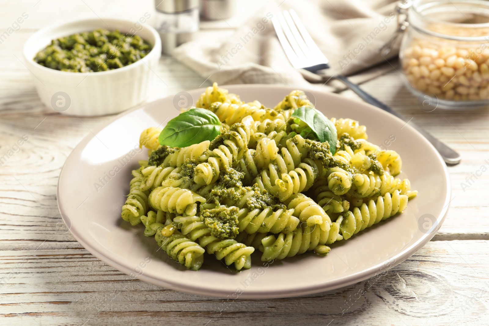 Photo of Plate with delicious basil pesto pasta on wooden table