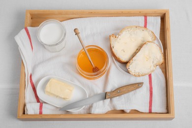 Photo of Sandwiches with butter, honey and milk on white table, top view