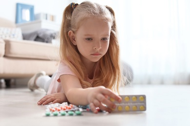 Photo of Little child with different pills on floor at home. Household danger