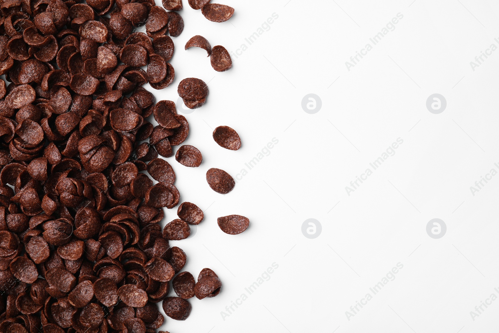 Photo of Breakfast cereal. Chocolate corn flakes on white background, flat lay. Space for text