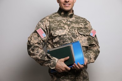 Cadet with books on grey background, closeup. Military education