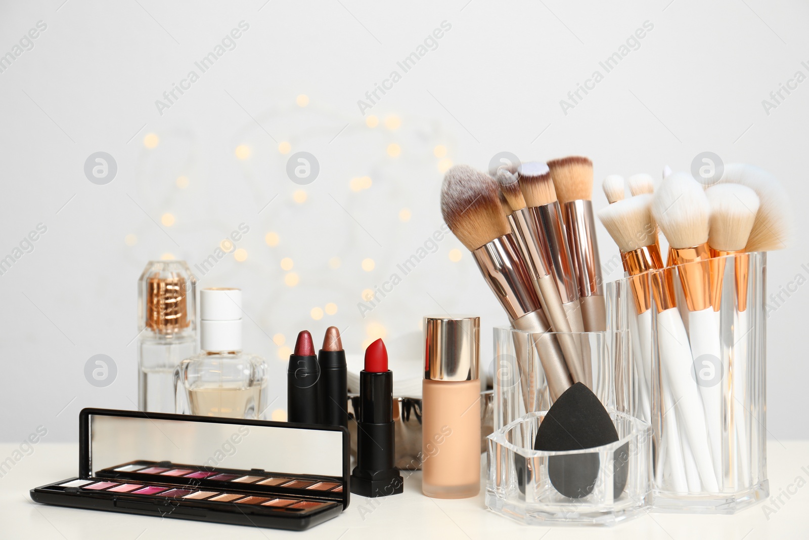 Photo of Set of cosmetic products and makeup brushes on dressing table