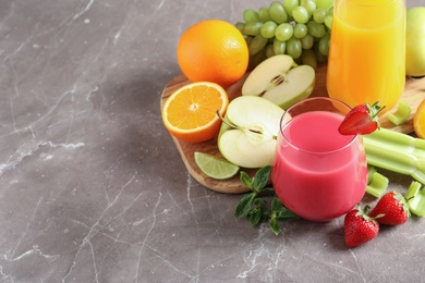 Glasses with different juices and fresh fruits on table. Space for text