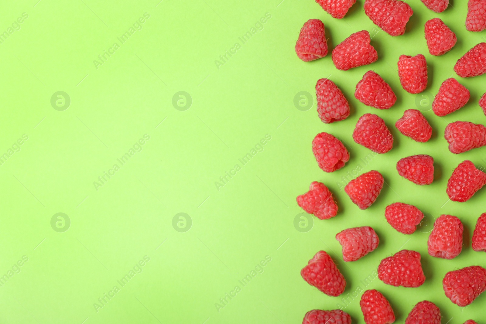 Photo of Flat lay composition with delicious ripe raspberries on green background. Space for text