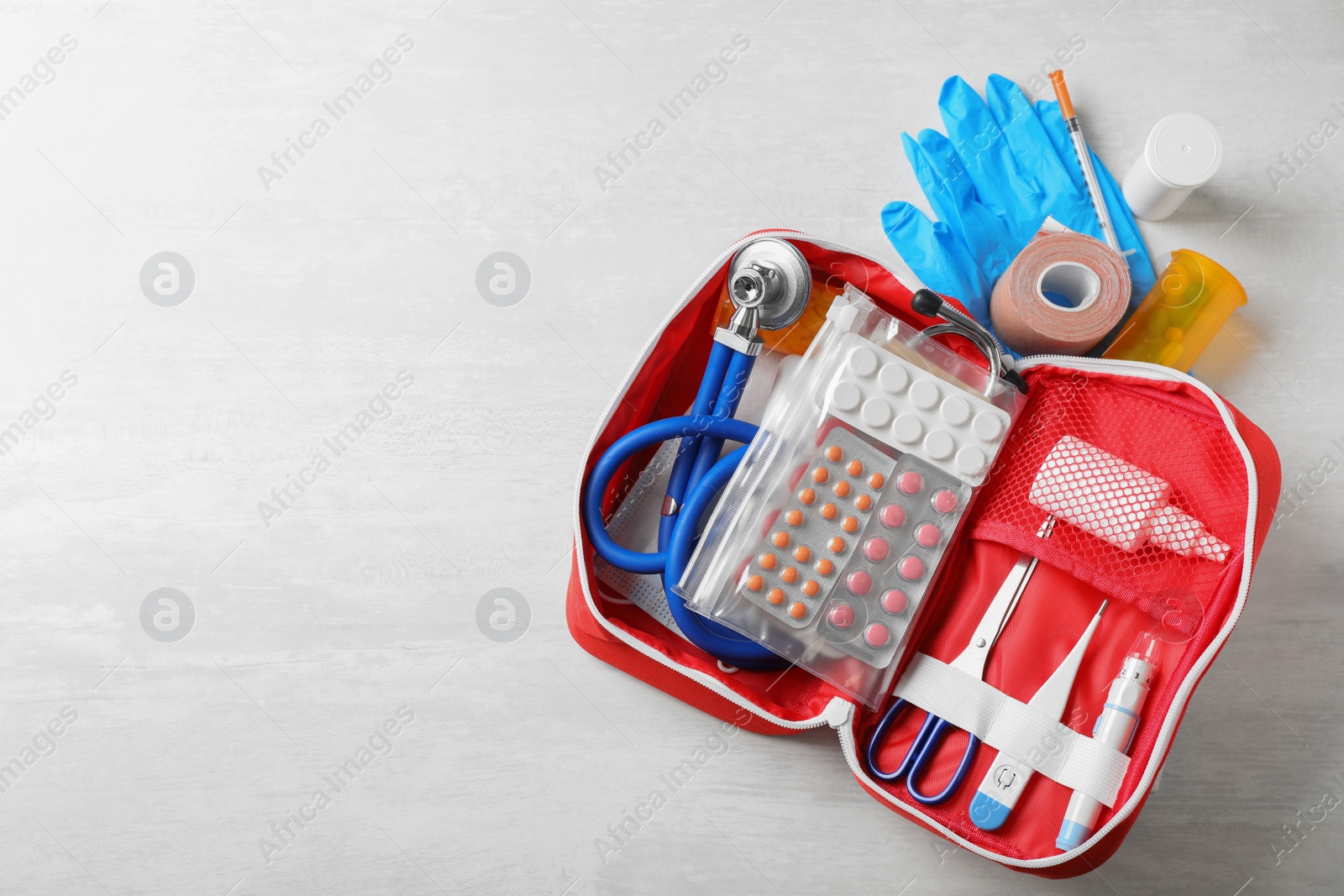 Photo of Flat lay composition with first aid kit and space for text on white wooden background