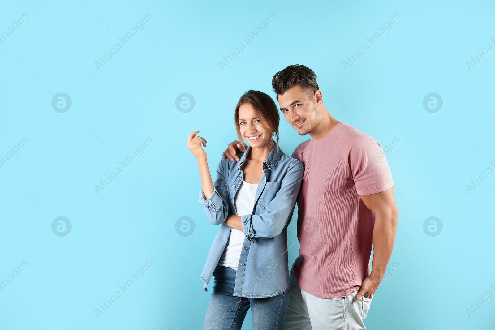 Photo of Young couple in stylish clothes on color background. T-shirts as mockup for design