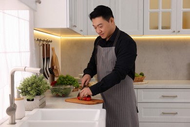 Cooking process. Man cutting fresh tomatoes in kitchen