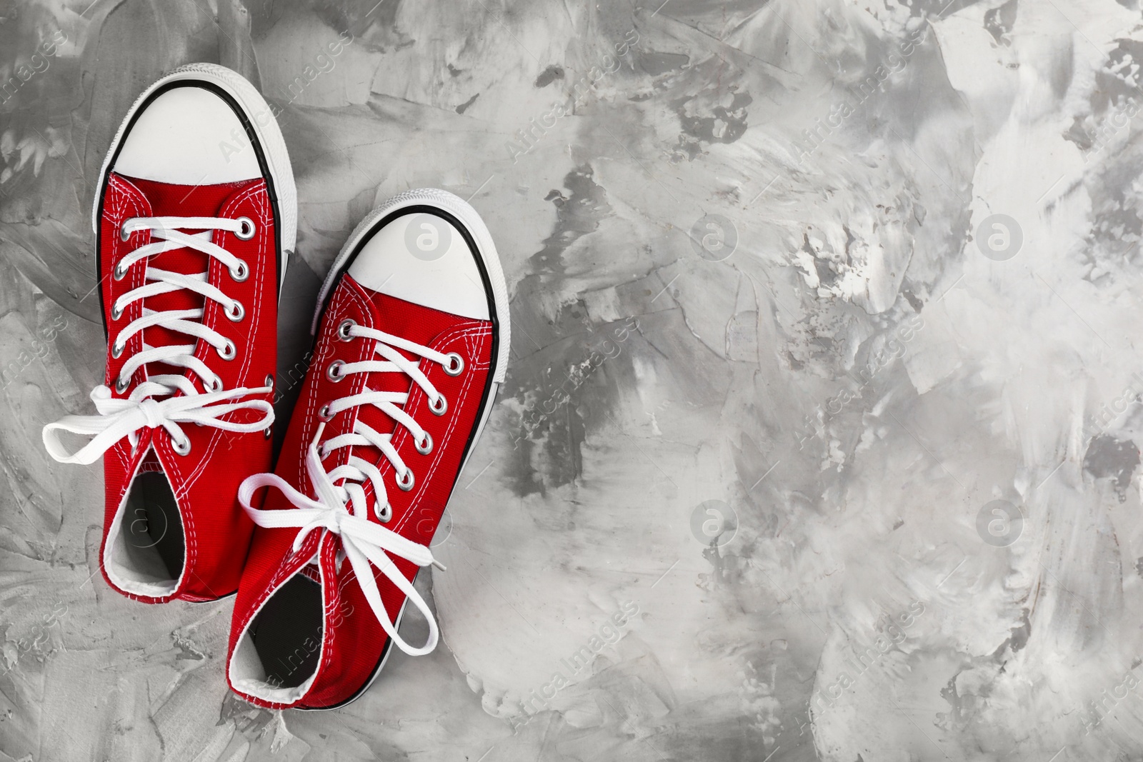 Photo of Pair of red sneakers on grey stone table, flat lay. Space for text