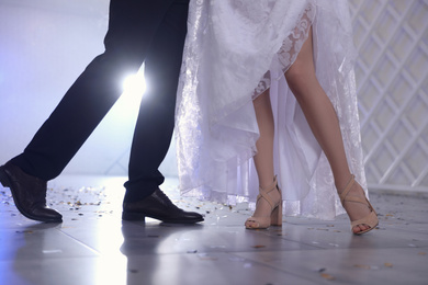 Photo of Newlywed couple dancing together in festive hall, closeup of legs
